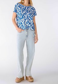 Blå og hvid mønstret top med korte ærmer, parret med lyseblå højtaljede jeans og brune platform sandaler.