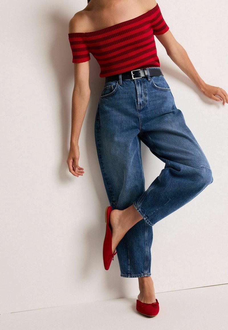 Red and black striped off-shoulder top, blue high-waisted jeans, black belt, and red flat shoes with bow detail; smooth fabric textures.