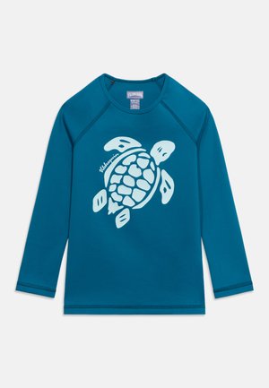 Chemise bleue à manches longues avec un grand graphique de tortue de mer bleu clair centré sur le devant et le texte « Vilebrequin » près de la tortue.