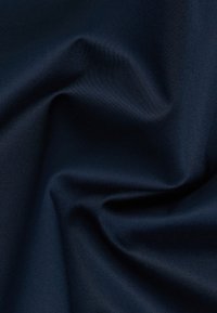 Tessuto blu navy con una texture liscia e setosa e una leggera lucentezza, caratterizzato da morbide pieghe e drappeggi, che indicano flessibilità e leggerezza.