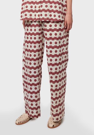 Pantalons en coton à motifs présentant un design géométrique avec des rectangles et des cercles rouges sur un fond crème. Coupe décontractée avec une texture douce.