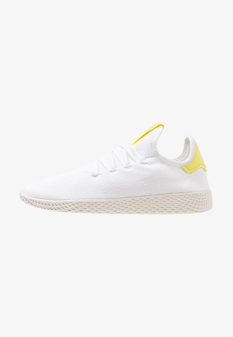 White athletic shoe with a textured mesh upper, yellow accents on the heel and tongue, and a patterned rubber sole.