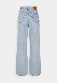 Jeans a gamba larga in denim azzurro chiaro con vita alta, dotati di due tasche posteriori e un'etichetta in pelle marrone chiaro sulla vita.