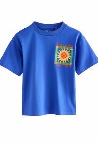 Blå kortärmad t-shirt med rund hals, med en färgglad solgrafik och texten "HOLA SOL" på en kvadratisk patch. Mjuk bomullsmaterial.