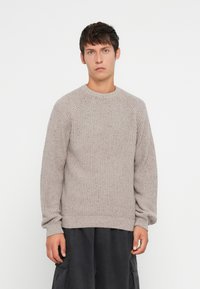 Maglione grigio chiaro in maglia con un motivo testurizzato, scollatura rotonda e orlo a coste. Presenta maniche lunghe e una vestibilità rilassata.