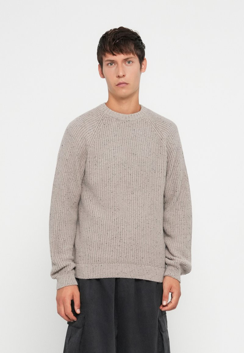 Maglione grigio chiaro in maglia con un motivo testurizzato, scollatura rotonda e orlo a coste. Presenta maniche lunghe e una vestibilità rilassata.