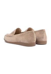 Beige suède loafers met lage, platte rubberen zolen, afgeronde neuzen en eenvoudige stikdetails, gezien vanuit een achterzijaanzicht.