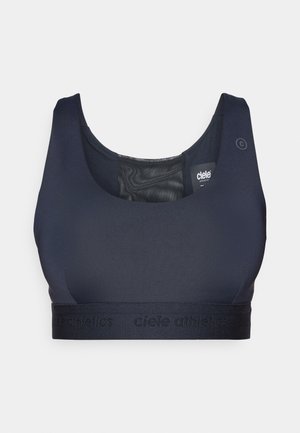 Reggiseno sportivo blu navy realizzato in un tessuto liscio e elastico. Presenta una fascia larga con logo in rilievo e un colletto arrotondato. La parte posteriore ha dettagli in rete.