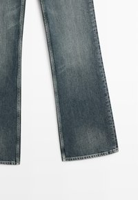 Džíny s širokými nohavicemi v bledě modré barvě, s hladkou strukturou, rovný střih a zesílené švy podél lemu.