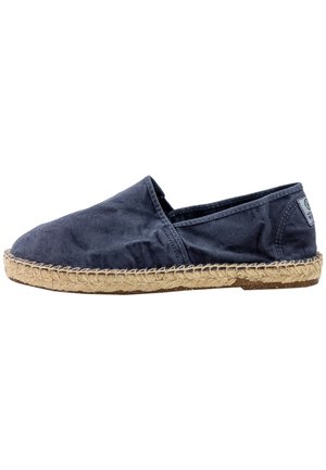 Zapatos slip-on de lona azul marino con punta redonda, suela de cuerda de yute y sin piezas metálicas visibles. Textura suave con sutilezas en las costuras.