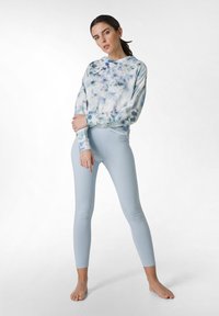 Felpa blu tie-dye con cappuccio, abbinata a leggins blu chiaro. Entrambi gli articoli hanno una texture morbida e un design aderente.