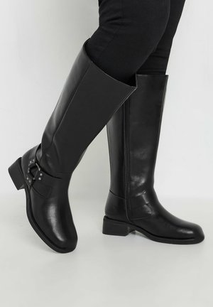 Black knee-high boots made of leather with a smooth finish, featuring a side zipper and a decorative buckle accent near the ankle.