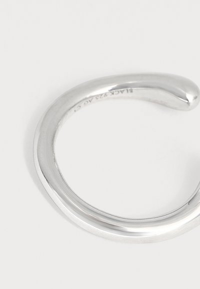 Bracelet manchette ouvert en argent lisse et poli avec extrémités arrondies sur fond blanc uni.