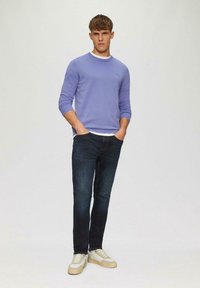 Lichtpaarse sweatshirt met ronde hals, donkere spijkerbroek en beige sneakers. Glad materiaal, slim fit ontwerp, met witte accenten op de halslijn.