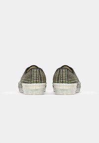 Instap schoenen met een geweven groen en beige patroon, zwarte accenten en een witte rubberen zool met een textuur voor extra grip.