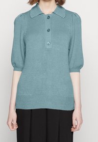 Světle modrý pulovr s krátkým rukávem, límcem, třemi knoflíky, žebrovaným lemem a manžetami a hladkým texturovaným materiálem.