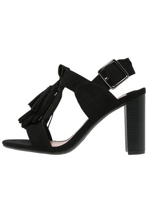 Sandal de tacón alto de ante negro con detalle de borlas, puntera abierta, correa en el tobillo ajustable y tacón bloque texturizado.