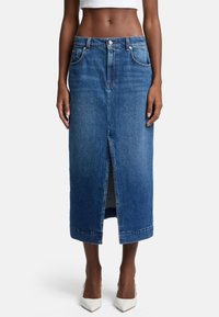 Jupe en denim bleu clair avec une fente frontale, design à cinq poches et taille ajustée. Présente des coutures visibles et une coupe classique.