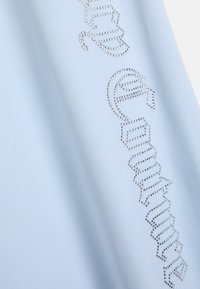 Svetlomodrá tkanina má zakrivenú líniu priehľadných rhinestone kamienkov, ktoré tvoria stylizovaný text, s hladkou, jemnou textúrou a jemne lesklým povrchom.