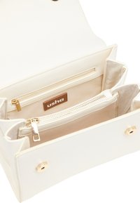 Hvid kunstlæder taske med beige for, der indeholder en lynlåslomme og et mærketag. Hardware i guld-tone accentuerer.