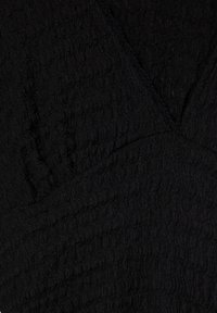 Schwarzer texturierter Stoff mit einem subtilen Wellenmuster, ausgestattet mit einem V-Ausschnitt-Design und sichtbaren Nähdetails, die einen schichtweisen Look erzeugen.