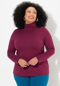 Burgundy long-sleeve turtleneck top in soft fabric, featuring a relaxed fit and a simple round hem, paired with teal leggings.