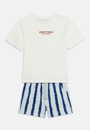 Hvid kortærmet skjorte med teksten "Good Times All Day Long" og lyseblå shorts med mørkeblå lodrette striber.