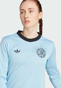 Light blue long-sleeve soccer jersey with ribbed texture, black collar, and Adidas logo. Features circular DFB branding on the chest.