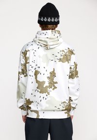 Sudadera con capucha en blanco con un patrón de camuflaje en beige y detalles en negro. Fabricada con un tejido suave y texturizado. Incluye un bolsillo canguro en la parte delantera.