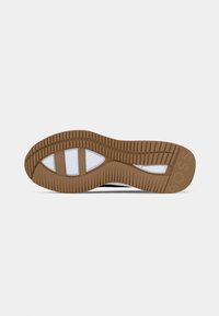 Sola della scarpa con battistrada in gomma marrone e sezioni bianche per la presa, mostrando un design a scanalature curve per aderenza e flessibilità.