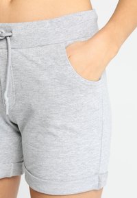 Ljusgrå bomullsshorts med dragsko i midjan och sidofickor. Shortsen har en rullad fåll och en mjuk, texturerad yta.