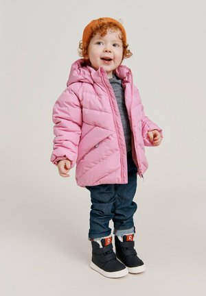 Giacca puffa rosa con cappuccio, caratterizzata da un motivo a rombi diagonali e tasche frontali. Abbinata a jeans scuri e scarpe nero alte.