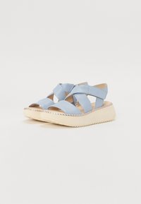Sandales en cuir bleu clair avec des lanières croisées, bout ouvert et une semelle en coin de couleur crème avec un bord texturé.