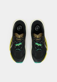 Chaussures de sport noires avec une tige en mesh texturé, des accents verts et jaunes, et des lacets contrastants dotés d'éléments réfléchissants.