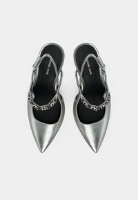 Ασημί μεταλλικά γοβάκια με λουράκι στον αστράγαλο και μυτερή μύτη, με μαύρο εσωτερικό και διακοσμητική αλυσίδα. Ομαλή υφή σε όλη την επιφάνεια.