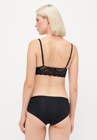 Black lace bralette with adjustable straps and matching high-waisted black panties. Soft fabric, intricate lace details, seamless design.