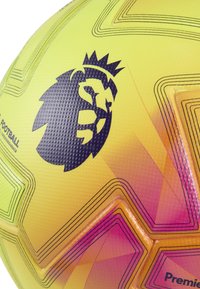 Pallone da calcio giallo con superficie texture, caratterizzato da un logo di un leone nero. Pattern geometrici in tonalità di rosa e arancione, che evidenziano i dettagli di design.