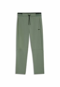 Grüne Trainingshose aus weichem Material mit einem Kordelzugbund, seitlichen Taschen und einem dezenten Logo-Detail auf dem Oberschenkel.