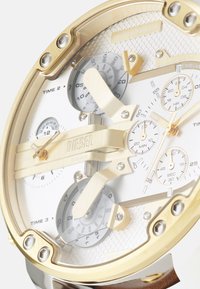 Orologio dorato con quadrante bianco testurizzato, multiple sotto-quadranti e cinturino in pelle marrone. Caratterizzato da lancette audaci e logo inciso.