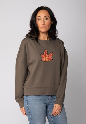 Olijfgroen sweatshirt met een grafisch oranje esdoornbladontwerp in het midden. Heeft een relaxte pasvorm en ribgebreide mouwen en onderkant.