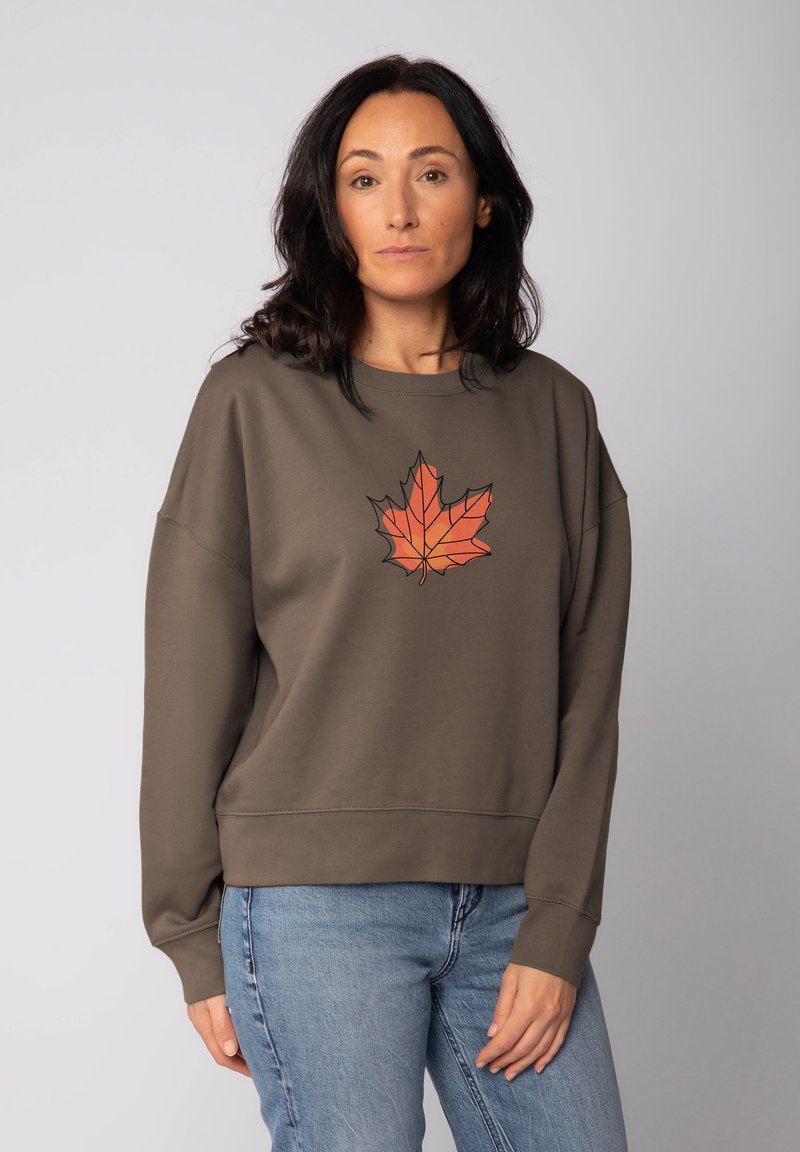 Olijfgroen sweatshirt met een grafisch oranje esdoornbladontwerp in het midden. Heeft een relaxte pasvorm en ribgebreide mouwen en onderkant.