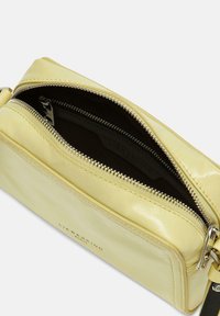 Borsa in pelle gialla con una texture liscia, dotata di una chiusura a zip singola e fodera interna nera con un delicato logo stampato.