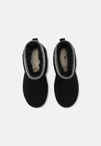 Sorte ankelboots laget av myk semsket skinn med en plysjforing, med en teksturert strikkekant rundt åpningen og en løkke for å dra i.