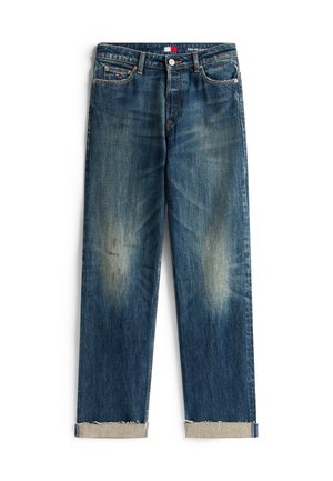 Jeans din denim albastru cu o croială lejeră, având decolorări la genunchi, tiv cu manșetă și o etichetă pe talie în roșu, alb și albastru.