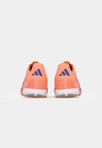 Scarpe sportive rosa-arancio con una tomaia testurizzata, suola bianca e accenti blu sul tallone e sui lati. Progettate per le prestazioni.
