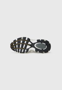 Sola de sneaker lacoste în alb și negru, având un material din cauciuc texturat cu modele circulare și ovale, și un detaliu al logo-ului în centru.