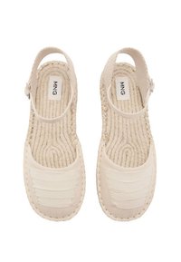 Beige sandaler med vävt mönster; har justerbart ankelsnöre och randig tygdetalj vid tån. Platt, bekväm design.