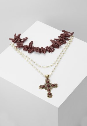 Collier à double rang avec un rang de perles brunes ressemblant à du corail et un autre de petites perles blanches, orné d'un pendentif croix en or incrusté de pierres brunes.