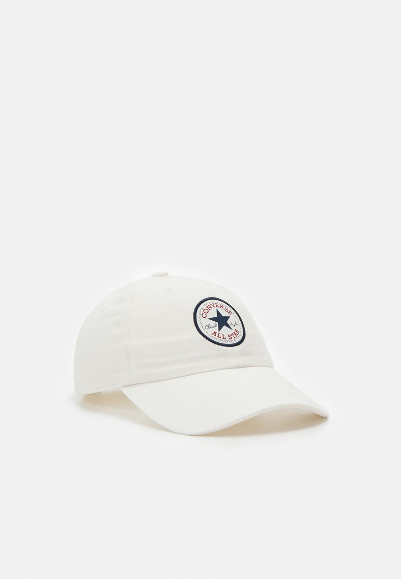 Cappellino da baseball bianco in cotone con visiera curva, dotato di un patch rotondo blu e rosso con la scritta "CONVERSE ALL STAR."