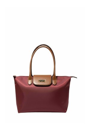 Sac cabas marron avec poignées en cuir marron et rabat, plaque de marque dorée et fermeture éclair sur le dessus sur fond blanc.